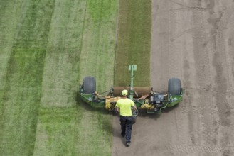 Workers laying grass in a roll on a football field at the stadium in Lubin, Poland, Europe