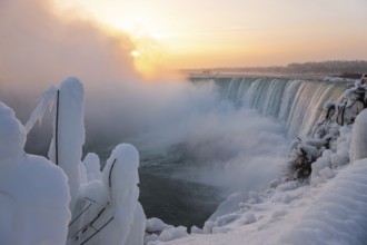 A frozen Horseshoe Falls at sunrise with mist and snow creating a calm and serene winter landscape