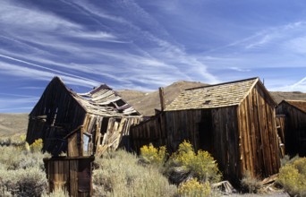 Windswept wooden houses in Bodie, collapsed by the weight of snow in winter. Colour photo,