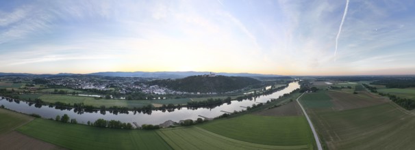 Panorama of a wide landscape with river, fields and hills at sunrise in the soft morning light,