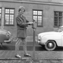 In the 1950s. A woman is pictured in the street and at a parking meter. A device used to pay for