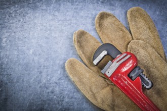 Pipe wrench safety gloves on scratched metallic background
