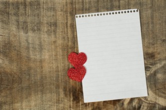 Red hearts and white paper sheet on wooden background