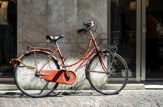 Red bike with basket on italian street. Typical italian architecture on background. Sunny day.