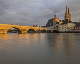 Serene riverside scene at sunset with a bridge, cathedral, and historic town reflecting on the
