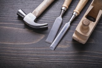 Claw hammer shaving plane and flat chisels on vintage wooden board construction concept