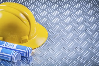 Blue engineering drawings building helmet on corrugated metal background construction concept