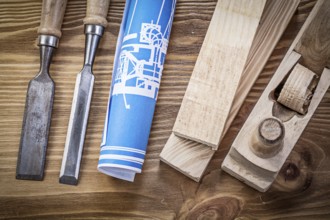 Blue rolled construction drawing shaving plane chisels wooden studs on wood board