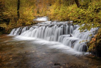 A beautiful autumn forest landscape with idyllic waterfall and pool