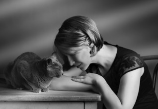 Portrait of a woman with her Russian Blue pedigree cat showing her affection