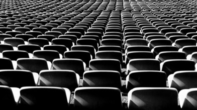 A black and white view of endless rows of empty chairs in a stadium
