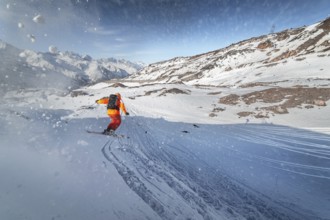 Skier rides on a snowy slope on a sunny day at sunset against the backdrop of the mountains. The