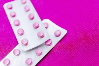 Pink pills in a blister on a pink background