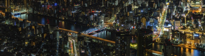 A paorama picture of the Sumida River and nearby cityscape, as seen from above, at night