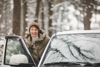 Cheerful female smiling and looking at camera while driving modern vehicle on blurred background of