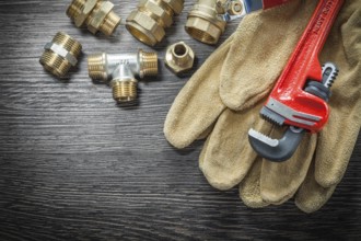 Plumbing monkey wrench pipe fittings protective gloves water valve on wooden board
