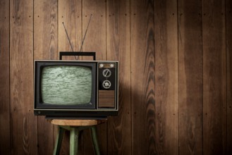 Old television in front of wooden wall