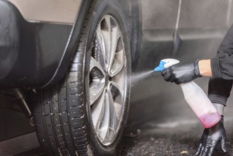 Professional car washer cleaning car alloy wheels