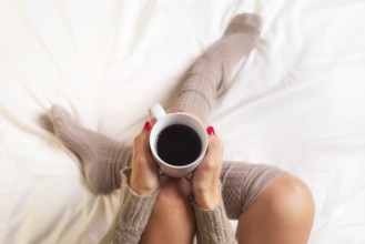 Woman sitting in bed drinking a cup of coffee