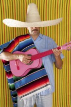 Mexican man with poncho and sombrero playing guitar typical of Mexico