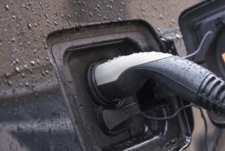 Electric car connected to charging station for recharging - close-up of charging station