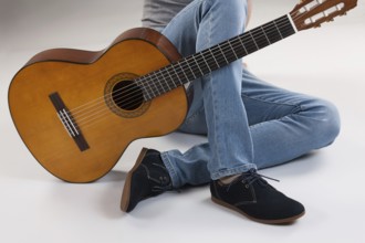 Man's legs and guitar on a studio background