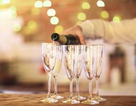 Champagne glasses on wooden table in bright lights. Party or celebration