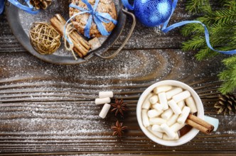 Flat lay Christmas background of blue mug with hot chocolate and marshmallows, spruce branch and