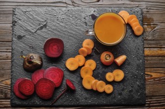 Top view at vegetable background of beets carrots and juice on kitchen table close up view