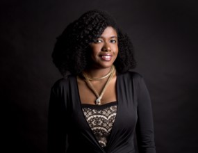 Beautiful young black woman is wearing dark dress on grey background, Toronto, Canada, North