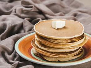 Close up view of homemade pancakes. Stack of pancakes with butter on brown concrete background