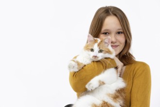 A cheerful girl lovingly holds her fluffy cat, radiating joy and warmth while wearing a cozy