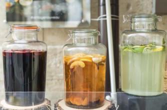 Glass jars filled with lemon, orange and apple juice on wooden stumps
