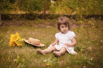 Little girl with sunflowers in a stetson on the garden