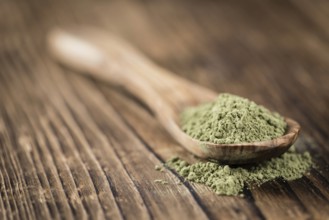 Portion of Stevia leaf powder (detailed close-up shot) on rustic wooden background