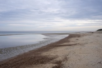 Calm beach with shallow water under a cloudy sky, Zeeland, Netherlands