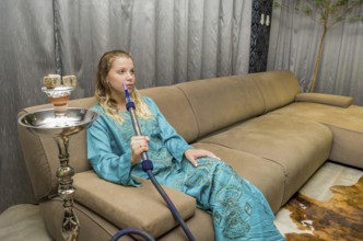 Woman smoking traditional Hookah (Narguile, Shisha, Chicha, Arguile), equipment used for smoking