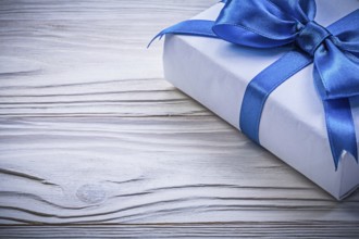 Present box with blue satin tape on wooden board celebrations concept