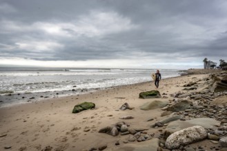 Ventura Beach, California, United States, March 1 2019: A surfer walking on the beach, North