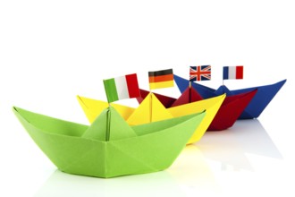 Colorful folded paper boats with European flags isolated over white background
