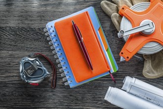 Construction drawings measuring tape protective gloves notepads pen on wood board