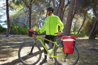 MTB Biker Bicycle touring in a pine forest with pannier racks and saddlebag