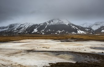 Icelandic landscape with frozen lake, mountains and meadow land covered in snow at snaefellsnes