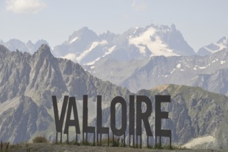 Name of Valloire write in metal letters, Valloire sign against a backdrop of majestic mountains and