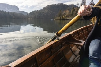 Young woman using paddle on a wooden boat, Lake Bled Slovenia rowing on wooden boats on a sunny day