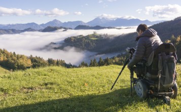 Man on wheelchair taking photos of beautiful landscape