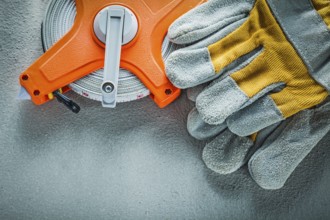 Safety gloves measuring tape on concrete background