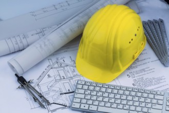 An architect's construction plan with a builder's helmet. Symbolic photo for financing and planning