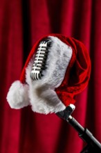 An old retro microphone with a Christmas hat in front of a red velvet background. Austria