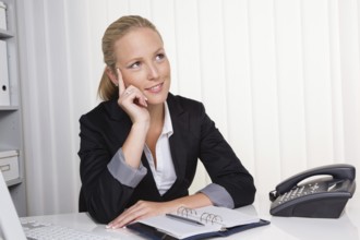 A young, successful businesswoman sits at her desk in her office in Austria